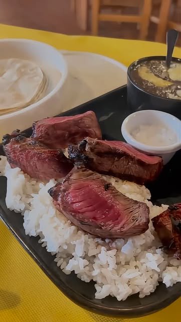 Corte de Angus a la brasa sobre arroz blanco con tortillas