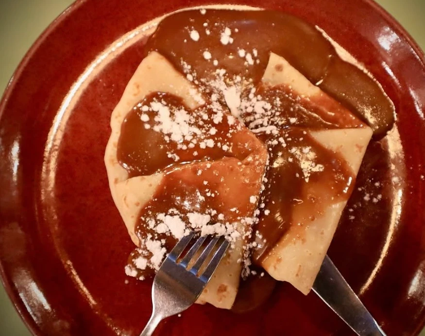 Crepas bañadas en cajeta con azúcar glas